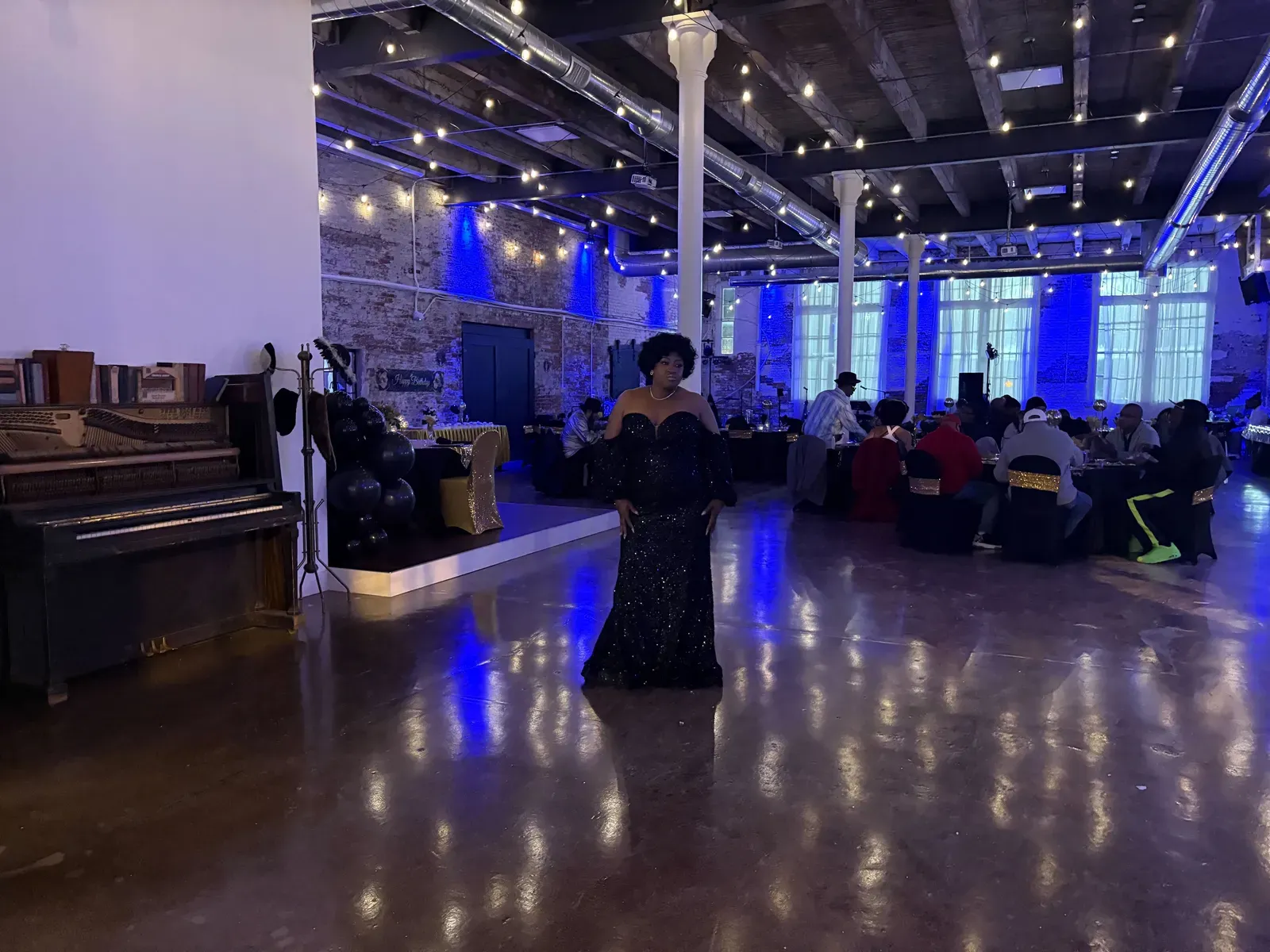 An evening fundraiser at 24 Shelby, a downtown Indianapolis event venue, with dramatic blue uplighting on the original brick and guests seated at tables