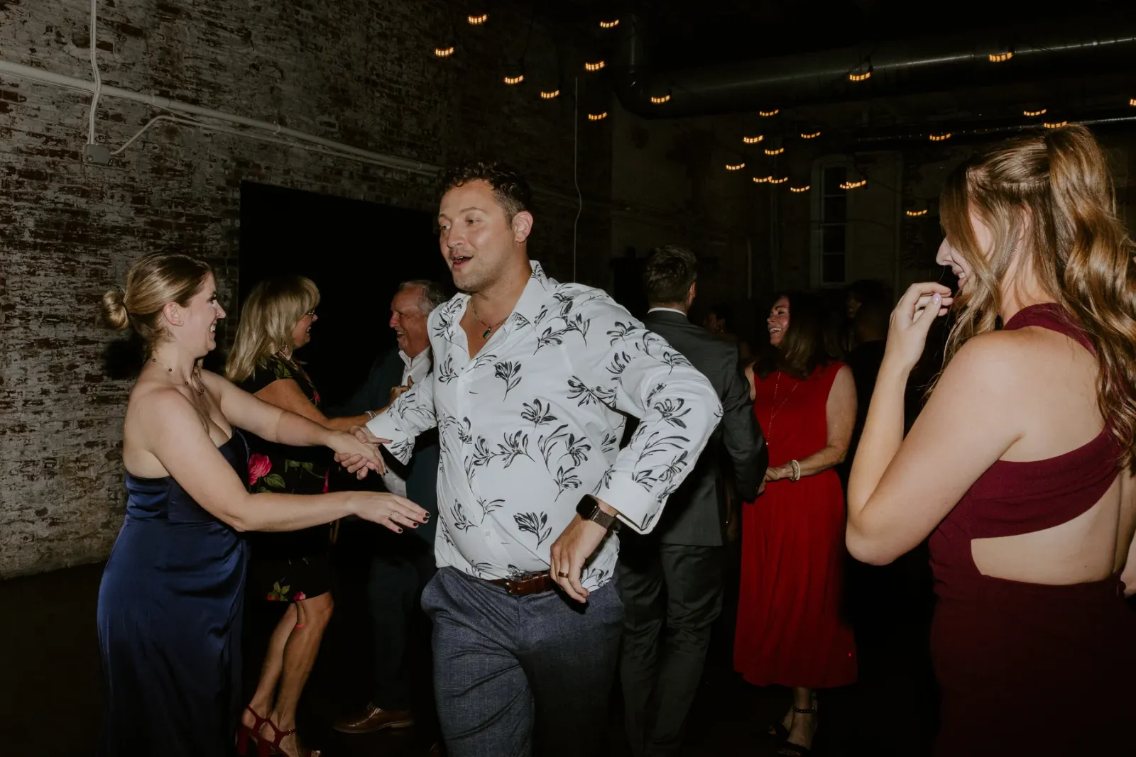 A packed dance floor at a downtown Indianapolis wedding reception under Edison string lights, the guest experience that matters more than decor when you plan an Indiana wedding on a budget.