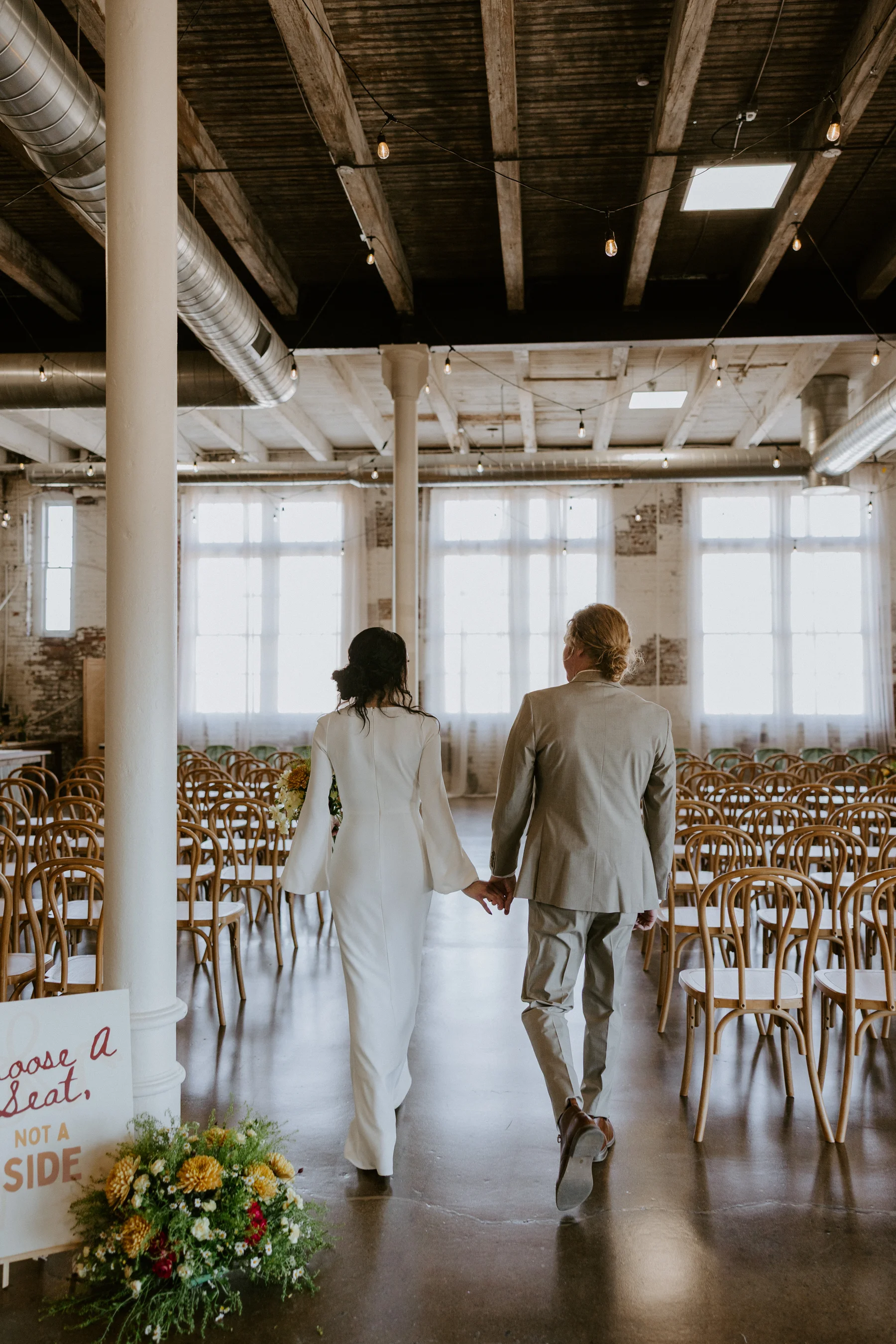 Wedding ceremony at 24 Shelby — string lights, wood beams, natural light